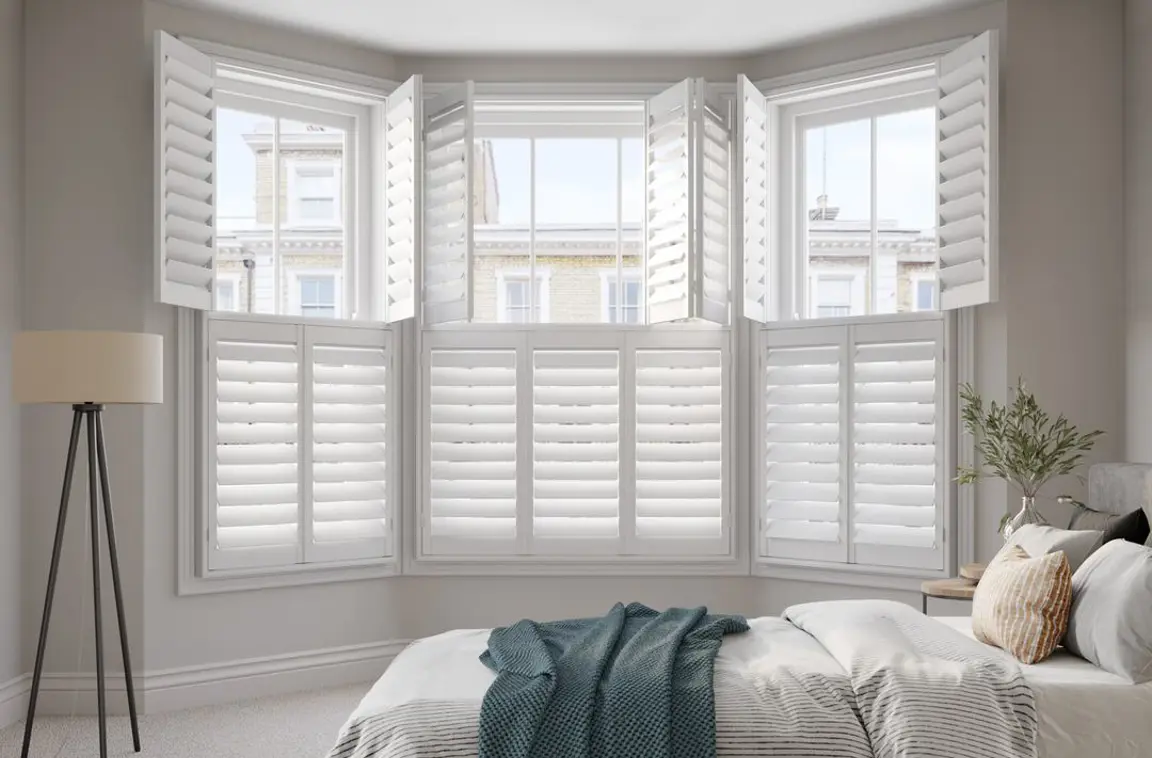 Vivid White bay window wooden shutters in neutral bedroom