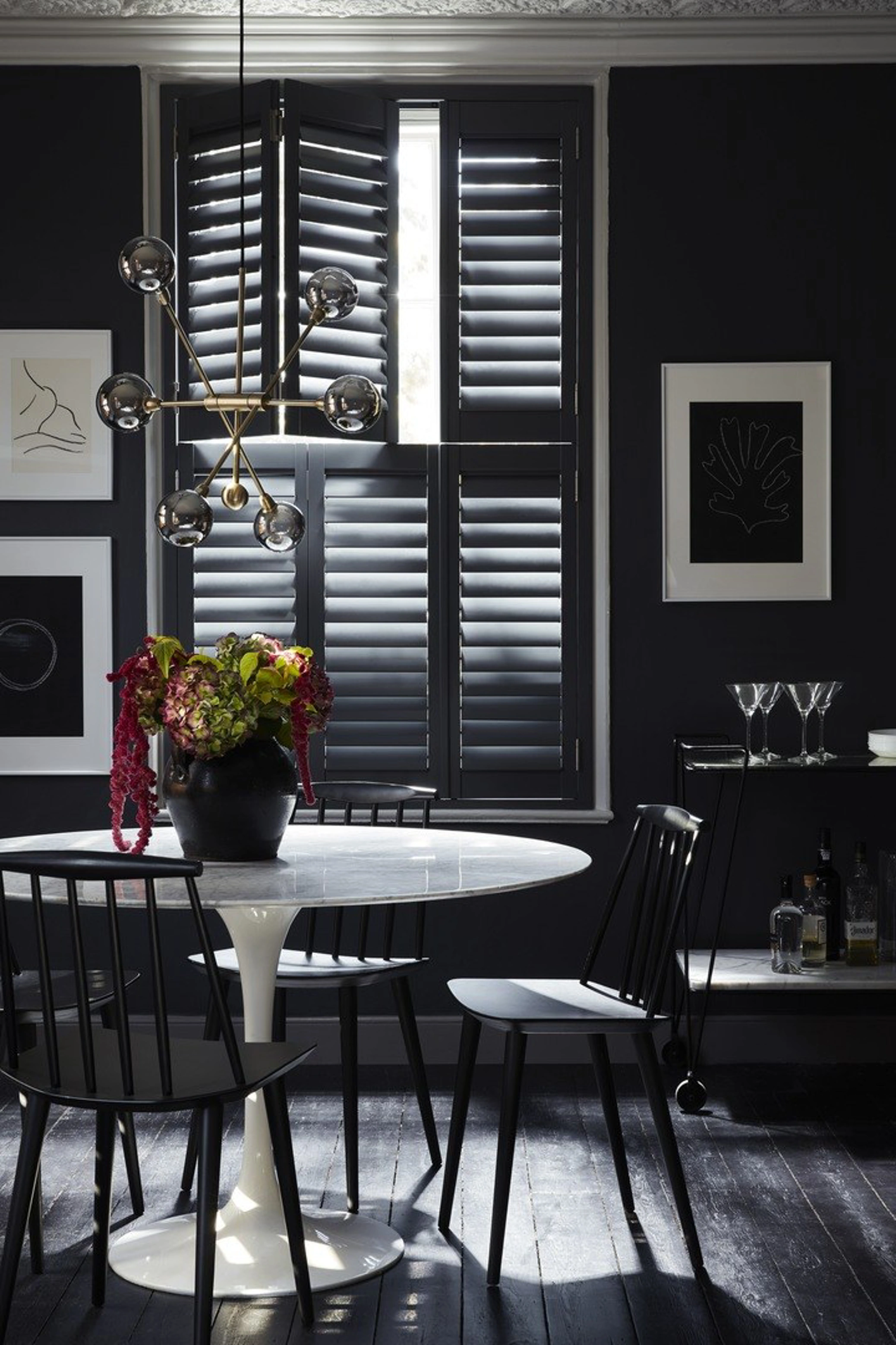 Tier on tier wooden black window shutters in dining room