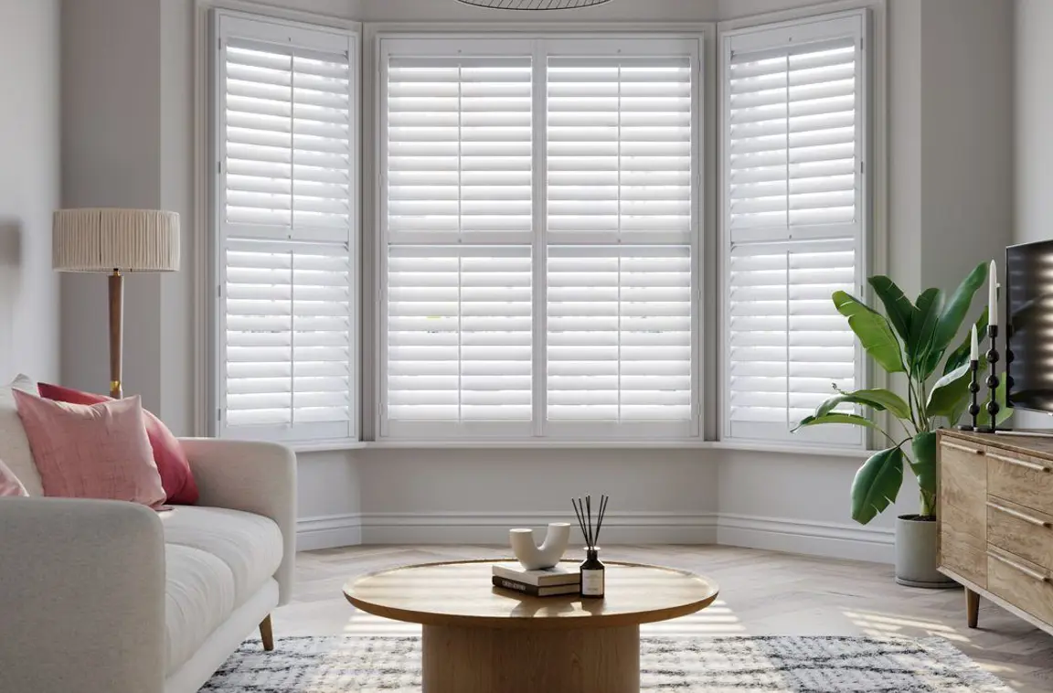 Vivid White wooden shutters on splayed bay with cream sofa