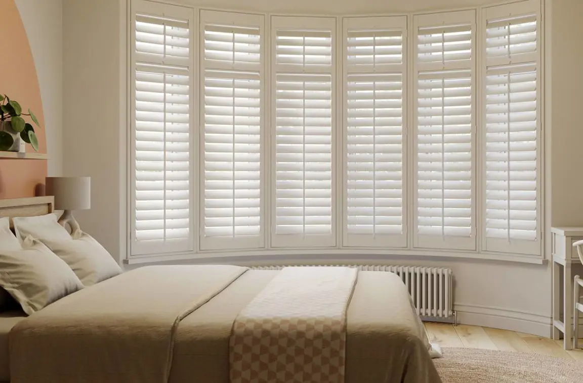 Vivid White full height wooden shutters on curved bay in neutral bedroom