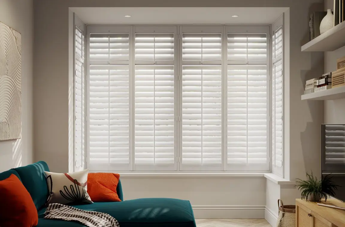 Vivid White box bay wooden shutters in living room with blue sofa