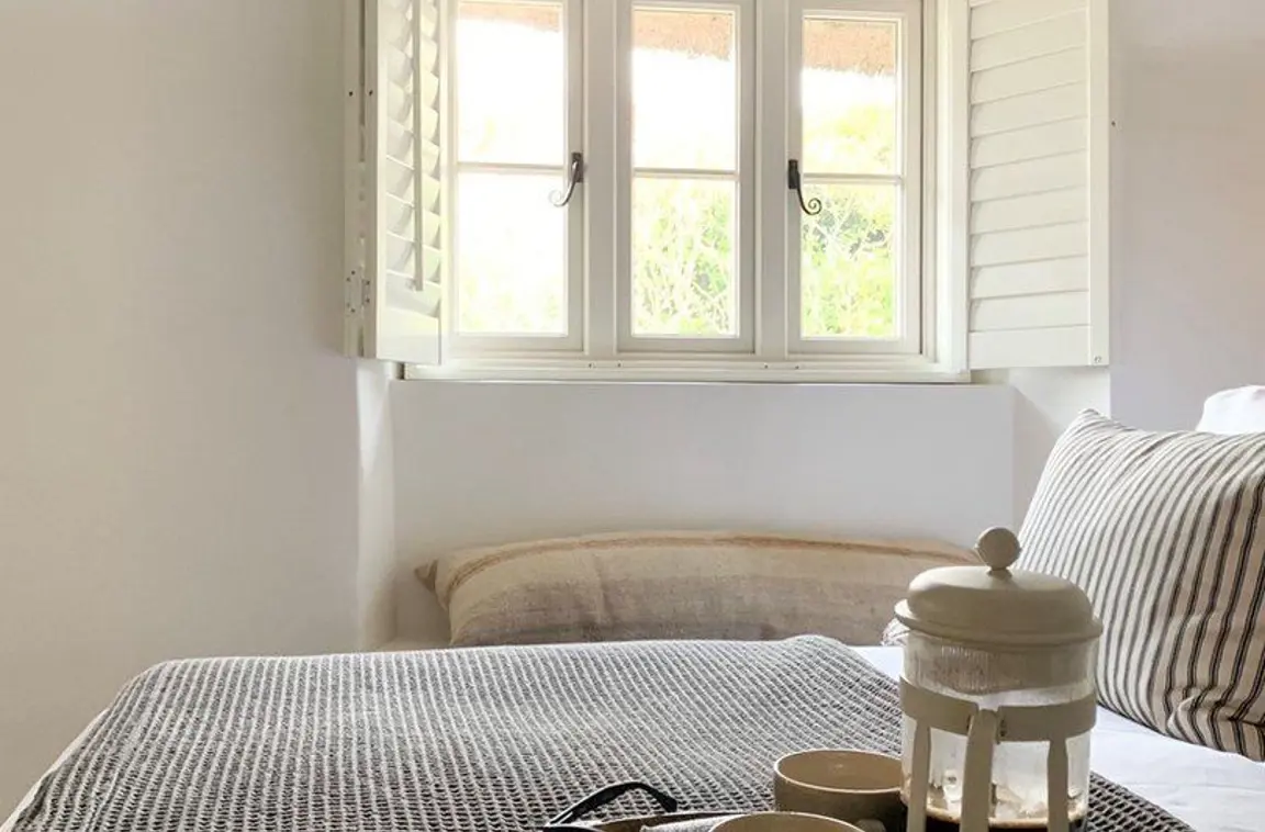 Traffic white cream wooden shutters in cottage bedroom