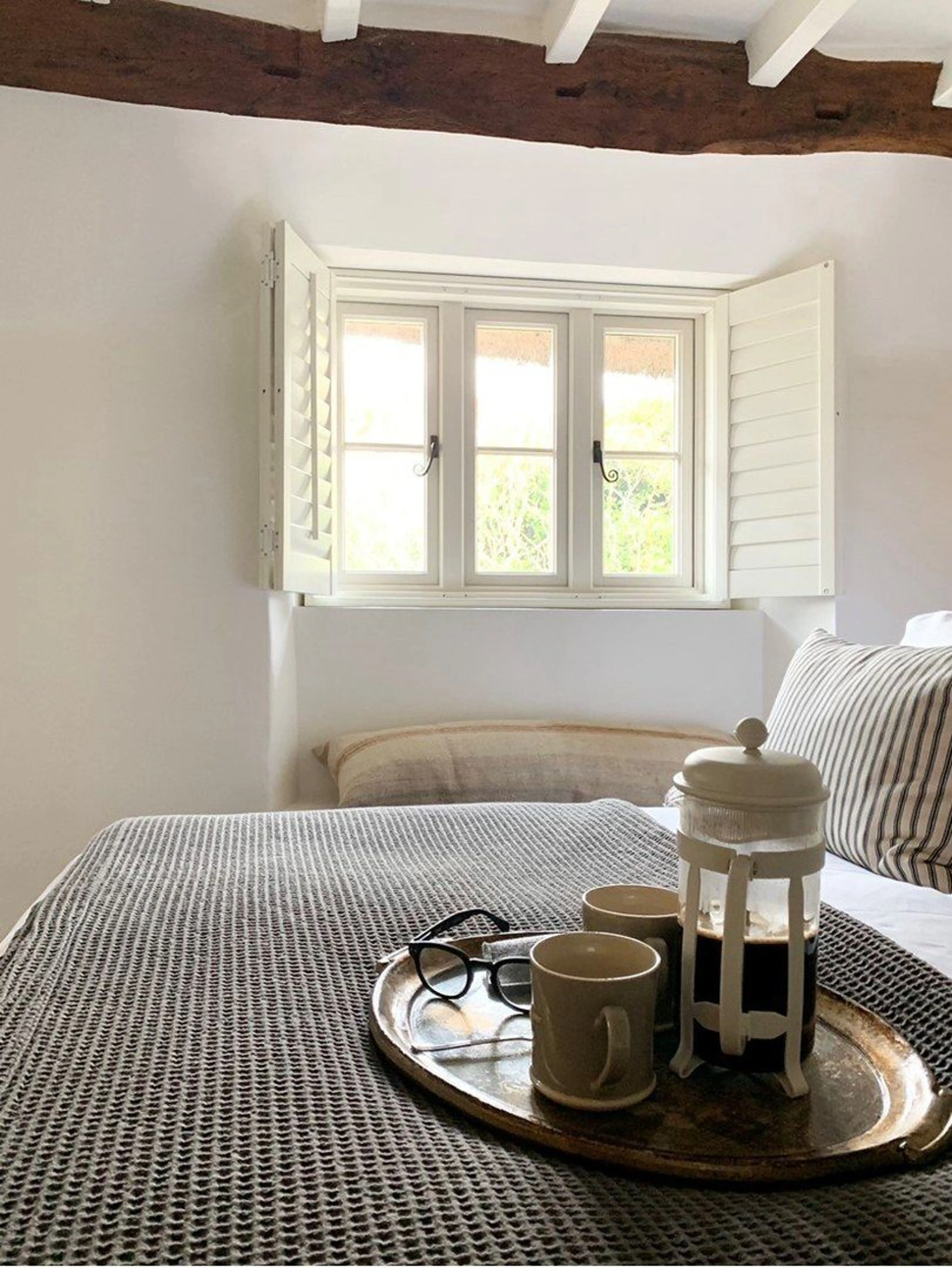 Traffic white cream wooden shutters in cottage bedroom