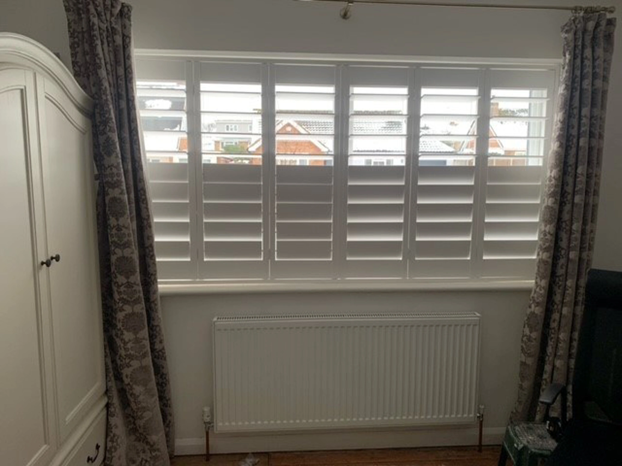 Vivid White wooden shutters with patterned curtains and large slats