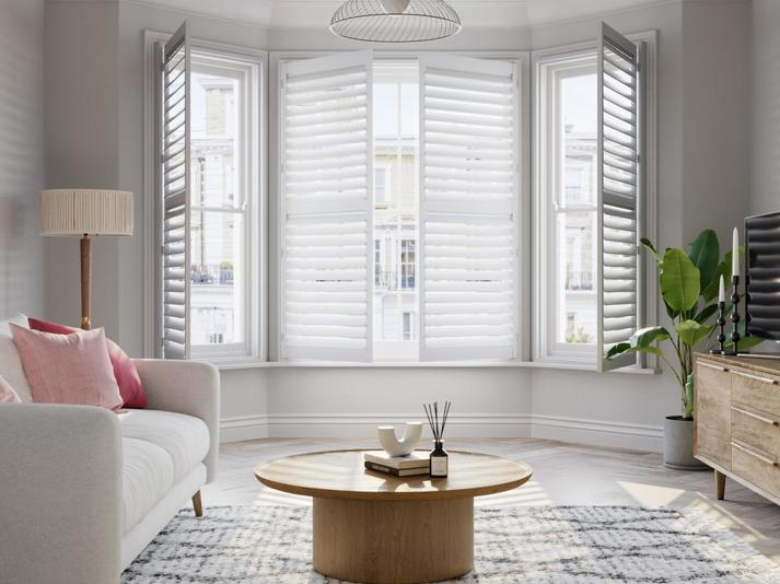 Vivid White wooden bay window shutters with cream sofa
