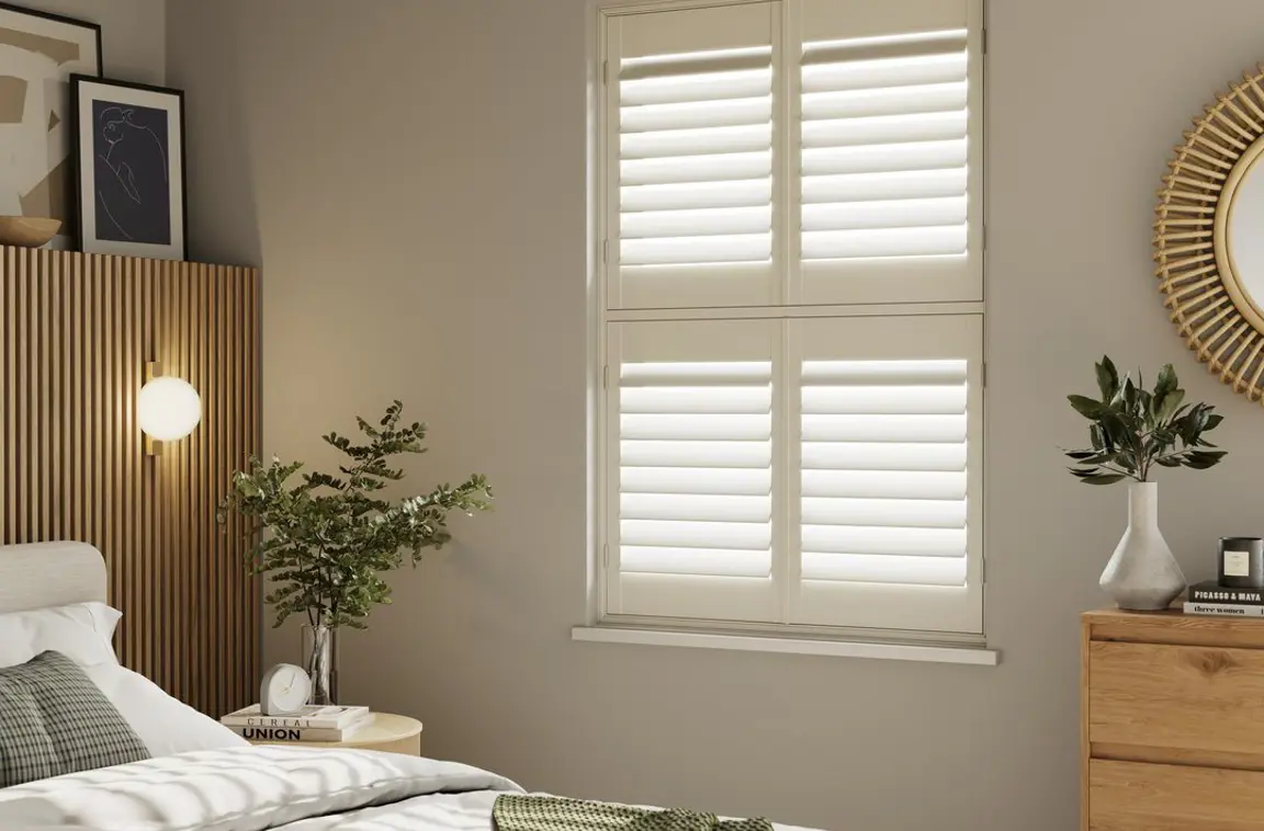 A neutral decorated bedroom with Cream tier on tier wooden shutters 