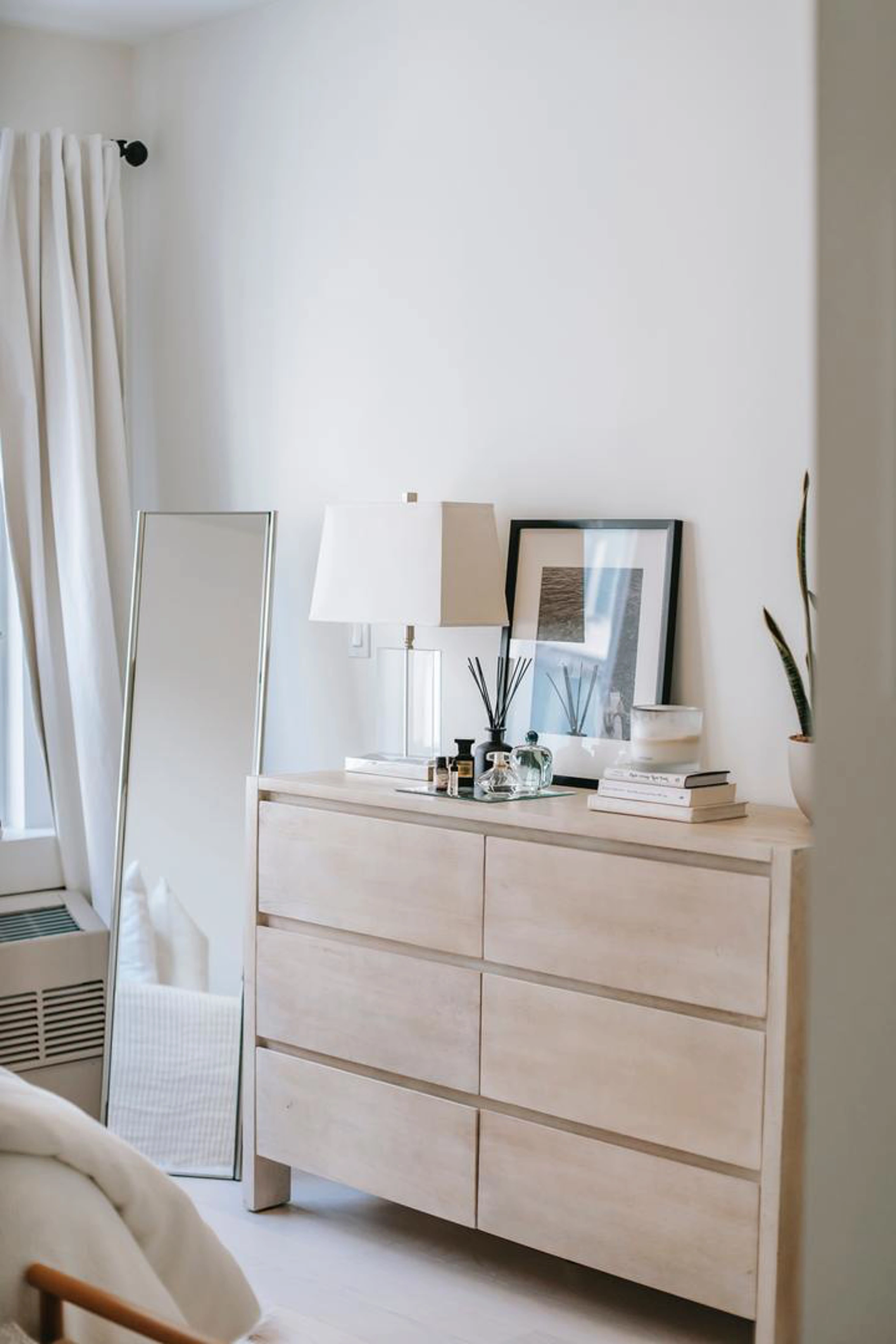 Light wood chest of drawers in bedroom with standing mirror